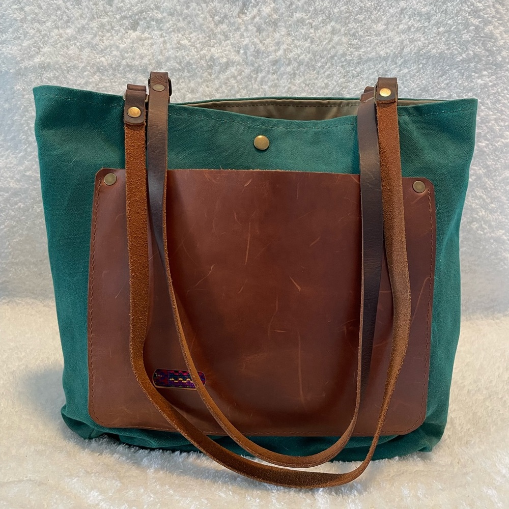 Teal waxed canvas tote with leather pocket and handles